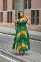 A model wearing a green and yellow Ankara striped African print Maxi dress by Heritage Clothings.