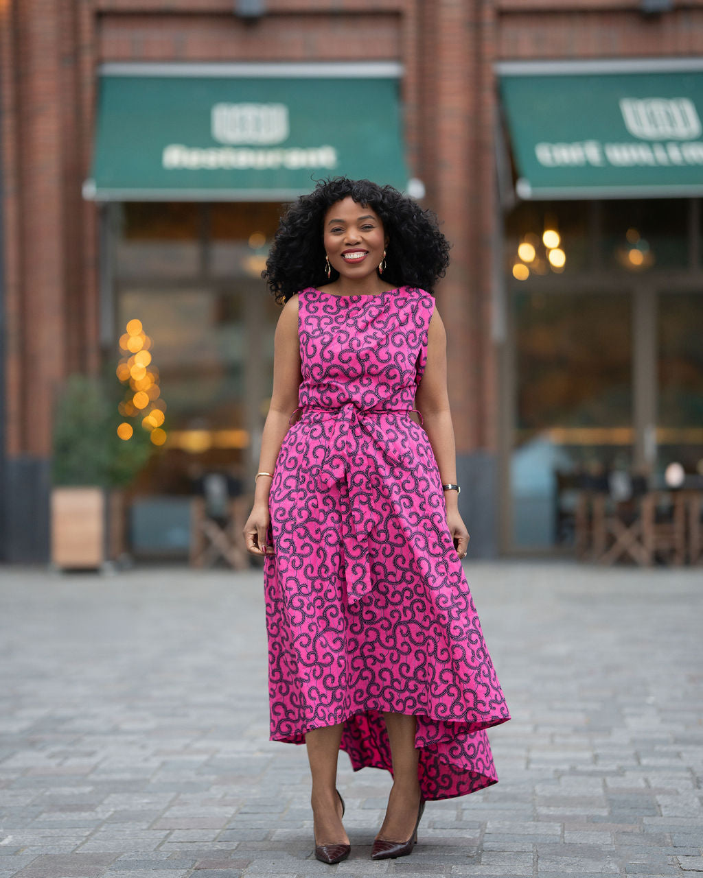 Model wearing a pink swirl African print Ankara Hi low Midi dress by Heritage Clothings