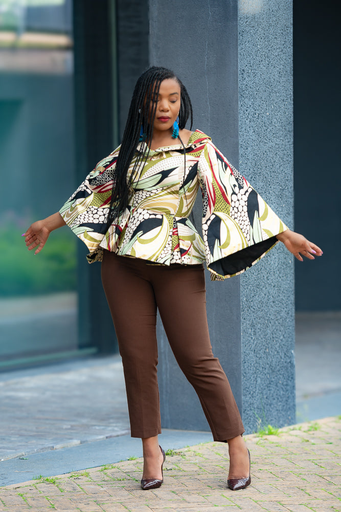 Model wearing small on the Zinitha floral top and brown pants standing outdoors.